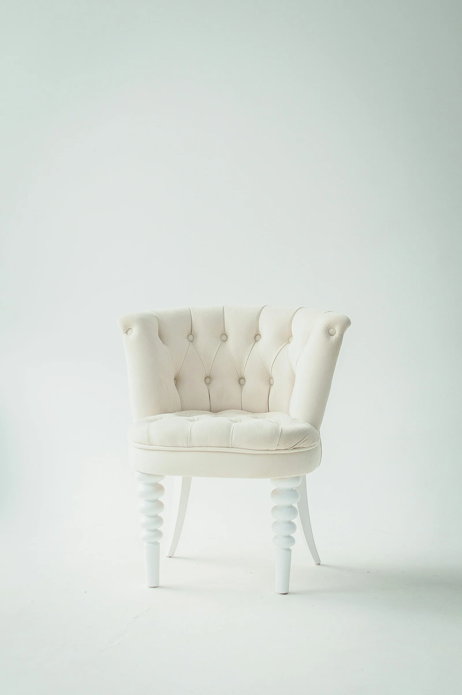 Photograph of a white tufted armchair